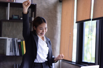 Portrait of female office worker celebrating on her accomplishment while standing at the office...