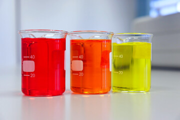 The beakers glassware on bench laboratory with red orange, yellow, colorful solvent from titration...