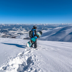Fototapeta na wymiar Snowboarder with snowboard in hand on mountain top. Winter freeride snowboarding
