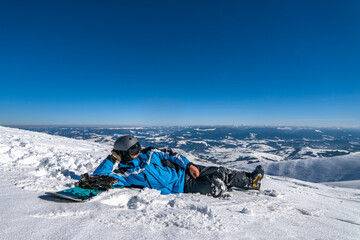 Snowboarder with snowboard relax on mountain top. Winter freeride snowboarding