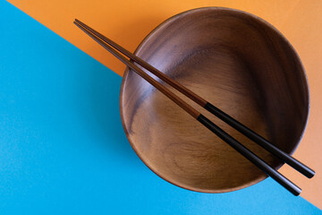 Asian wooden bowl, wooden plate, with chopsticks and without on Abstract pastel colored paper,...