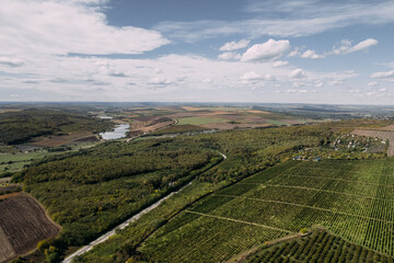 Aerial top view of the black soil autumn fields with small lake and cloudy sky. Drone shot of an autumn rural agriculture fields with harvest.