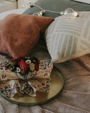 Vertical shot of a bouquet on a sofa with a blanket and pillos
