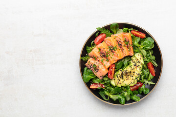 Salmon fish fillet with fresh salad, avocado top view.
