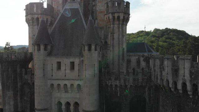 Aerial rising of Butron Castle facade revealing lush mountains. Gatika, Basque Country