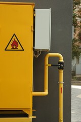 Yellow gas distribution cabinet near brown wall outdoors