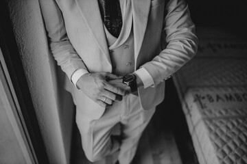 Elegant man in a suit checking the time on his wristwatch, a grayscale shot