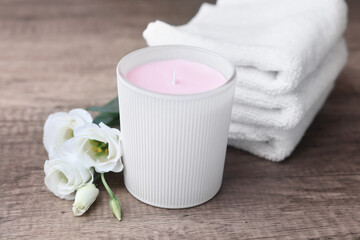 Obraz na płótnie Canvas Scented candle, folded towels and eustoma flowers on wooden table