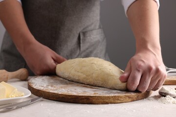 Man kneading dough at table near grey wall, closeup