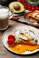Delicious toast with poached egg and avocado served on wooden table