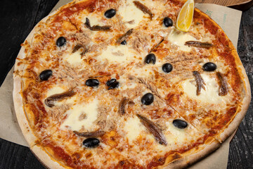 delicious pizza with cheese, greens, sauce in a restaurant
