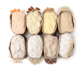 Paper bags with different types of flour on white background, top view