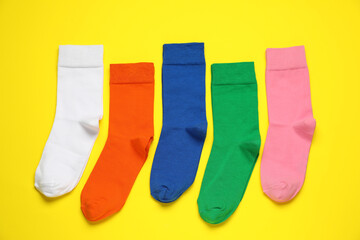 Different colorful socks on yellow background, flat lay