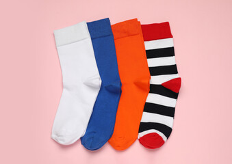 Different colorful socks on pink background, flat lay