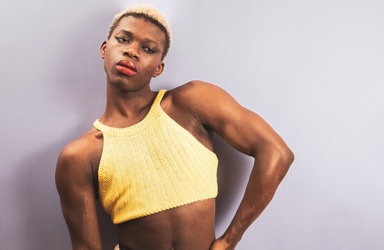 A young African man posing in a purple studio in yellow clothing. androgynous man.