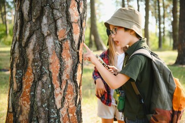 Naklejka premium Kids exploring nature with magnifying glass. Summer activity for inquisitive child.