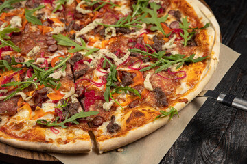 delicious pizza with cheese, greens, sauce in a restaurant
