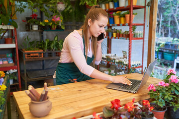 Floristin mit Smartphone und Laptop im Blumenshop online