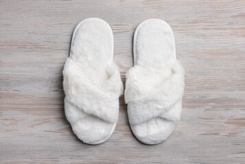 Fototapeta na wymiar Pair of soft slippers on white wooden floor, top view