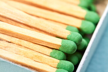 Close-up of Many matches with green heads in a matchbox on a blue background with copy space