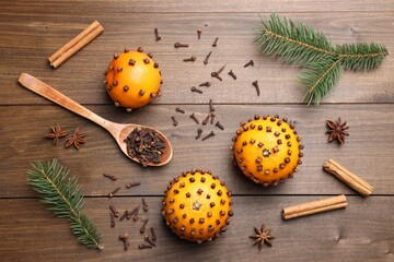Pomander balls made of tangerines with cloves and fir branches on wooden table, flat lay - Powered by Adobe