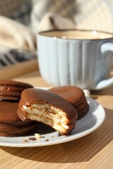 Tasty choco pies and cup of hot drink on wooden tray