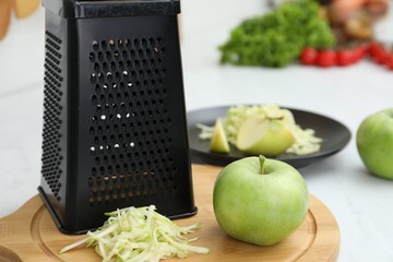 Grater and fresh ripe apple on wooden board, closeup
