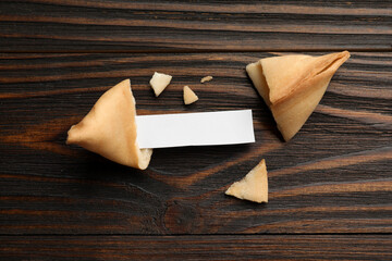 Tasty fortune cookie and paper with prediction on wooden table, flat lay. Space for text