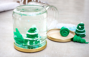 Kid Christmas activity. Homemade snow globe made from empty jar, glitter and polymer clay