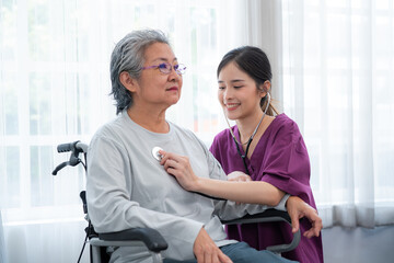 Obraz premium Asian young nurse taking care and talking mature female patient sitting on wheelchair in hospital. Healthcare concept.
