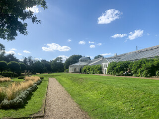 Green house at Chiswick House and Gardens, London. Fragment of facade of Grade1 listed greenhouse housing historic camelia plants at Chiswick House and Gardens in West London. Sunny day, bench in bush