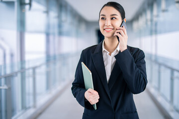 Asian woman with smartphone walking against street blurred building background, Fashion business photo of beautiful girl in casual suite with smart phone. 