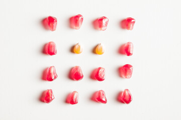 pomegranate and corn seeds isolated composition on white background