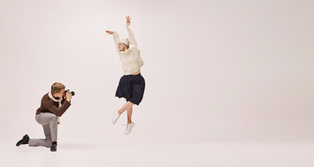 Ease of movement. Young stylish photographer taking picture of graceful young ballerina isolated on grey background. Retro, vintage, dance, holidays, party concept