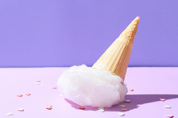 Waffle cone with sweet cotton candy on purple background