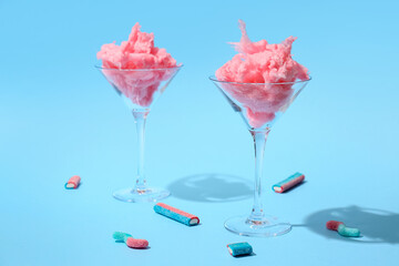 Glasses with delicious cotton candy on color background