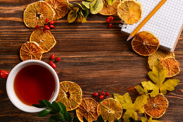 Frame made of notebook, cup of tea and autumn decor on wooden background