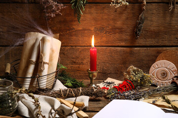 Magic attributes for ritual and burning candle on table against wooden background