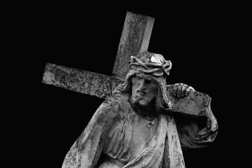 The road to Golgotha. Ancient statue of Jesus Christ with cross.