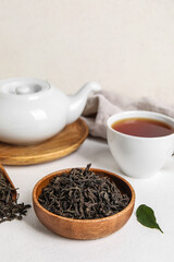Composition with dry tea leaves and hot beverage on white table
