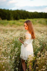 Fototapeta na wymiar A girl in a wreath of daisies at sunset