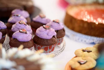 Poster Selective focus of chocolate cupcakes with violet topping on the festive table, blurred background © Burgie/Wirestock Creators