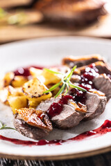 Culinarily prepared duck breast with baked potatoes and cranberry cauce.