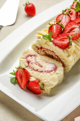 Plate with delicious strawberry roll cake on table, closeup