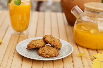 Aesthetics fall teapot and cup of healthy sea buckthorn tea with pumpkin vegan cookies. Herbal increased immunity natural tea. Healthy breakfast at the terrace in garden.