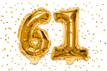 The number of the balloon made of golden foil, the number sixty one on a white background with...