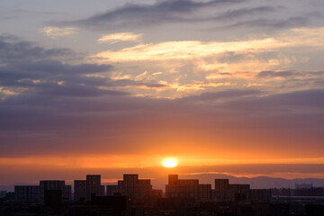 兵庫県神戸市東灘区の高層マンションの上層階からの夜明け。大阪生駒山から太陽が昇り、あたりはオレンジ色に染まり、ビル群がシルエットで浮かぶ