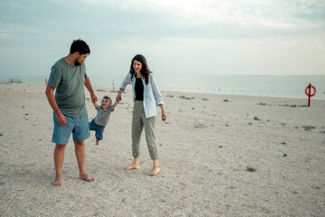 Happy family in the descent. Mom, dad and baby walk along the seashore.