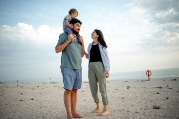 Happy family in the descent. Mom, dad and baby walk along the seashore.