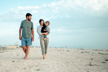 Happy family in the descent. Mom, dad and baby walk along the seashore.